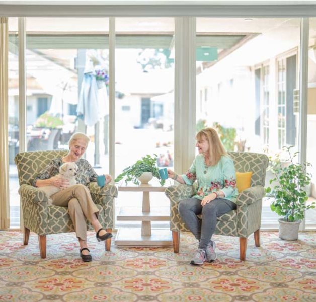 A happy seniors laughing together on the private, sunlit balcony of their Glendale Senior Apartment.